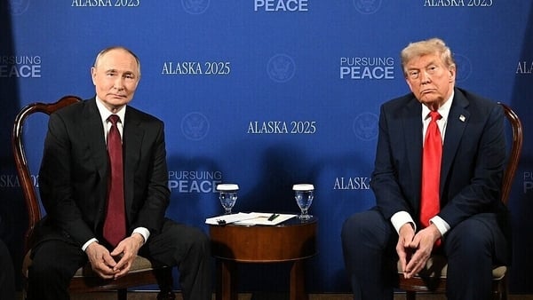 Vladimir Putin sits next to Donald Trump